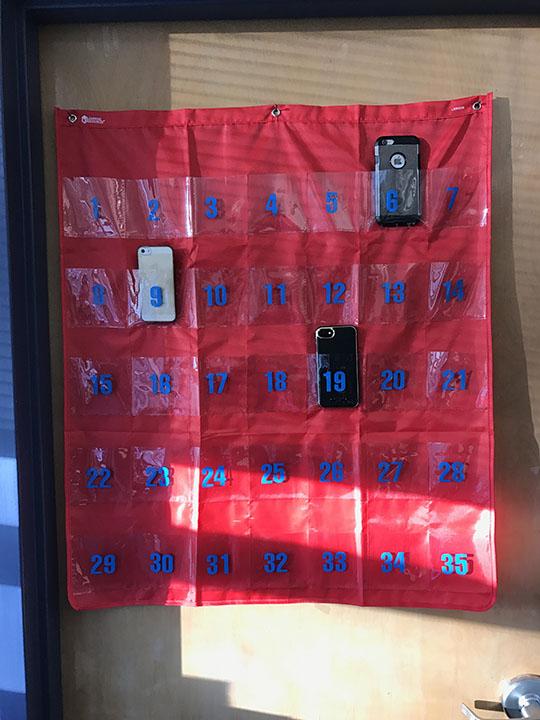 A "phone cubby" hangs sparsely populated in Mrs. Hall's classroom.