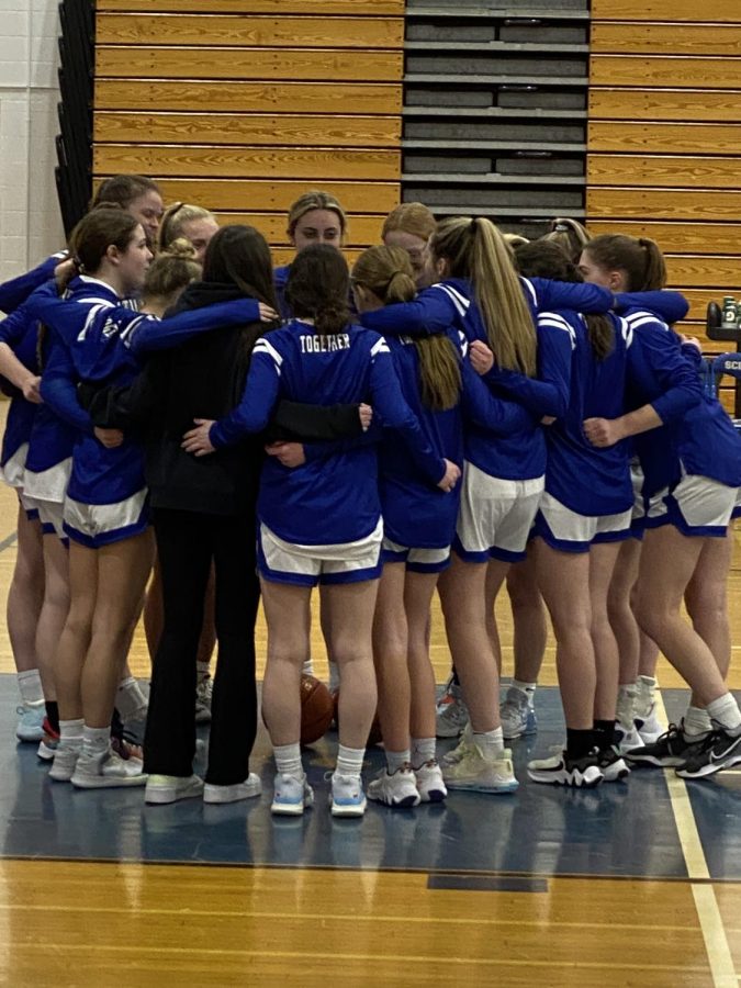 Girls varsity basketball teammates huddle before their final home game of the season