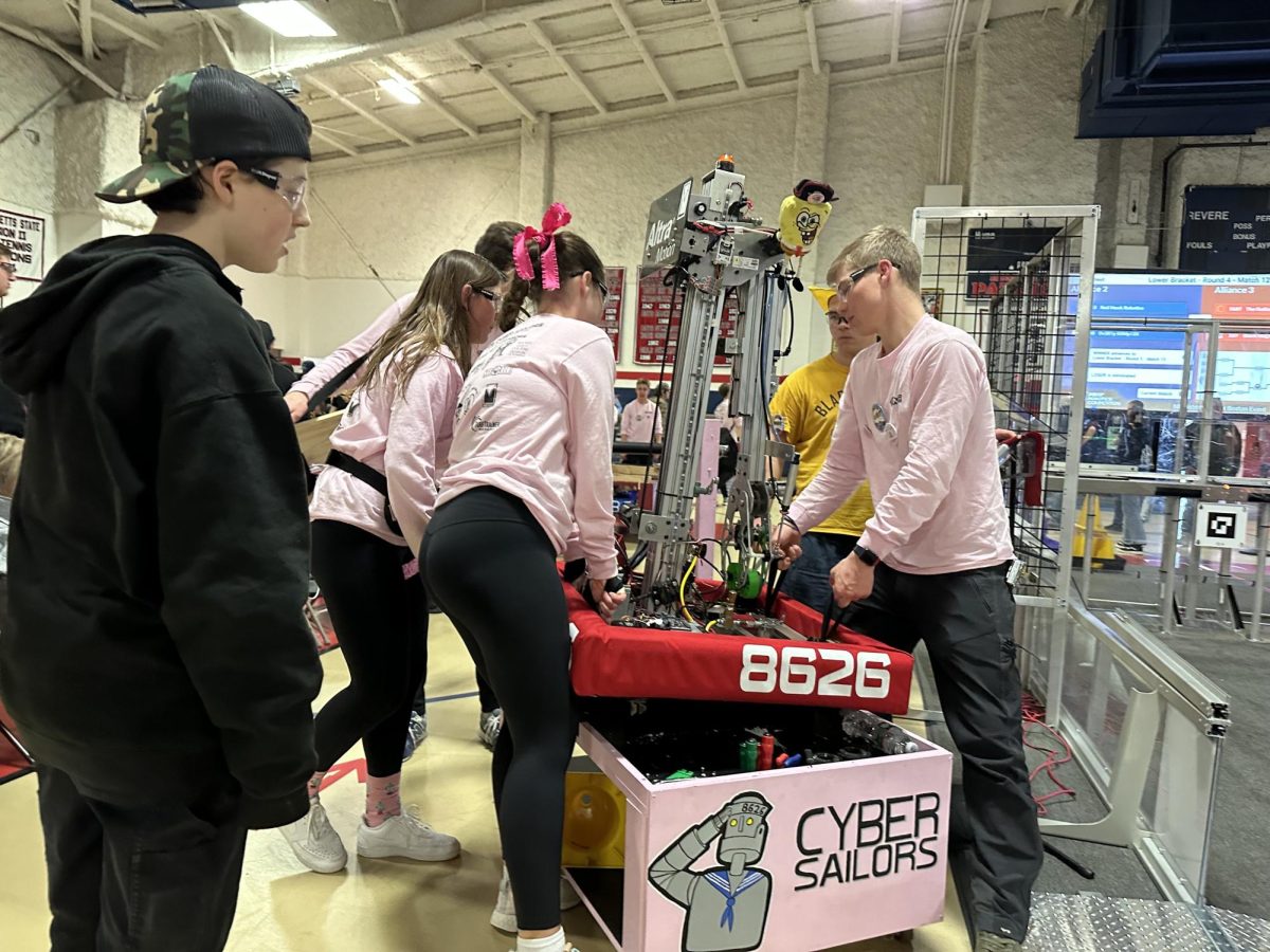 Robotics team members transfer their 2023 robot, "Goose," to the field. This year's robot is named "Dart."